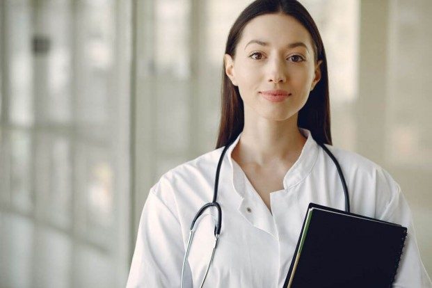 Woman wearing a stethoscope and holding a notebook