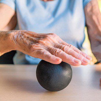 Person rolling a smaill medcine stress ball on the table