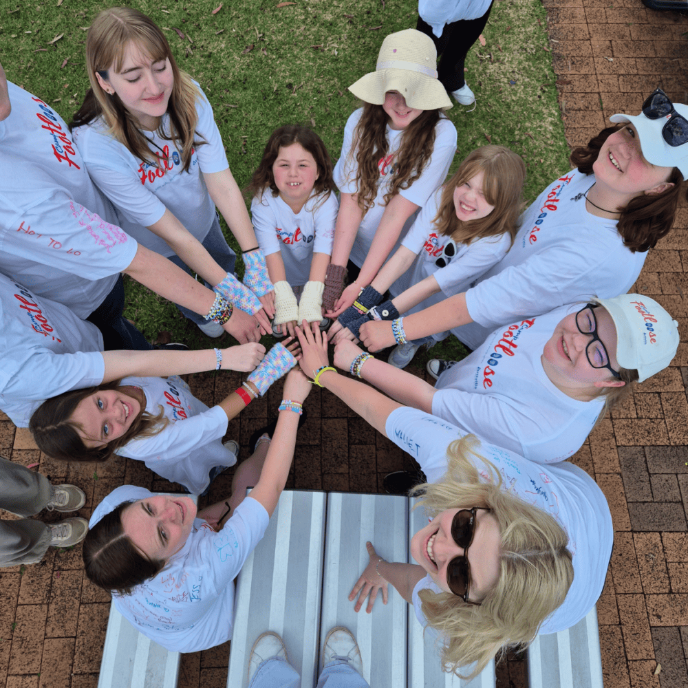 Participants of various ages at Camp Footloose, wearing camp t-shirts and putting hands in together