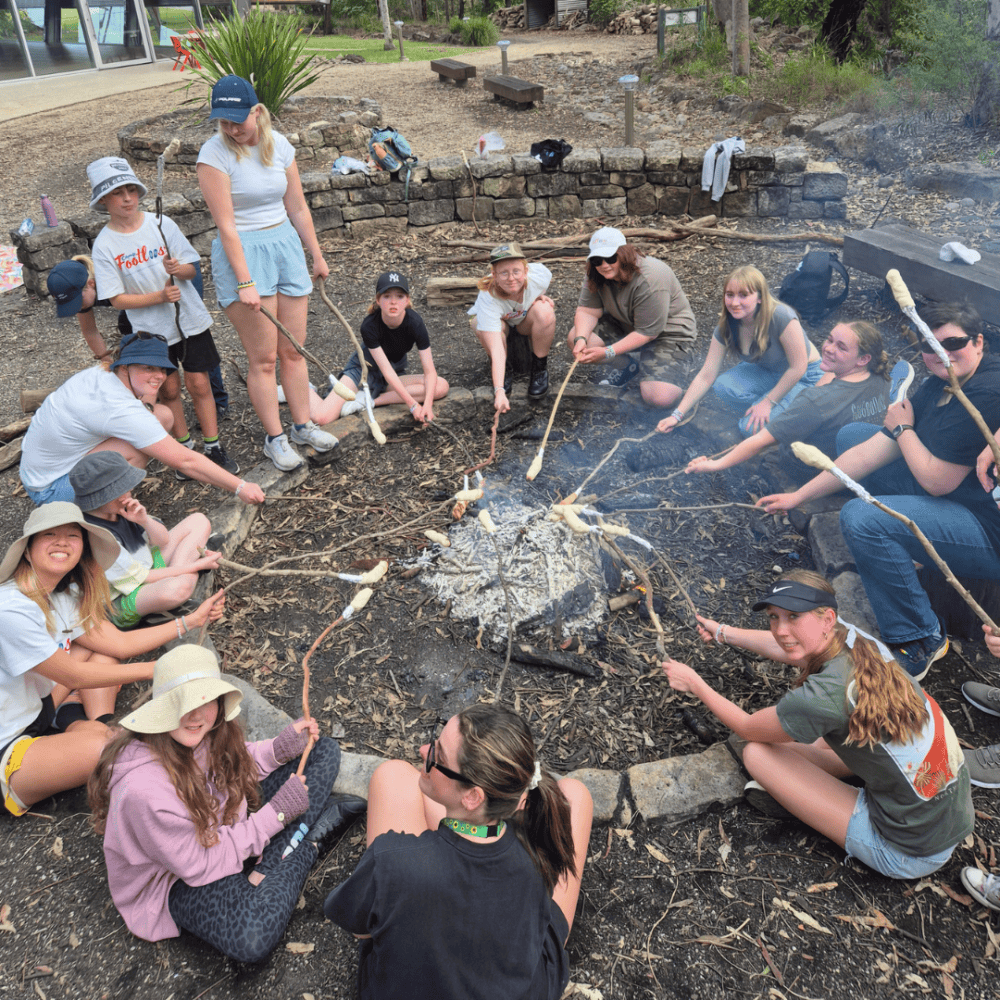 Kids toasting marshmellows around a camp fire
